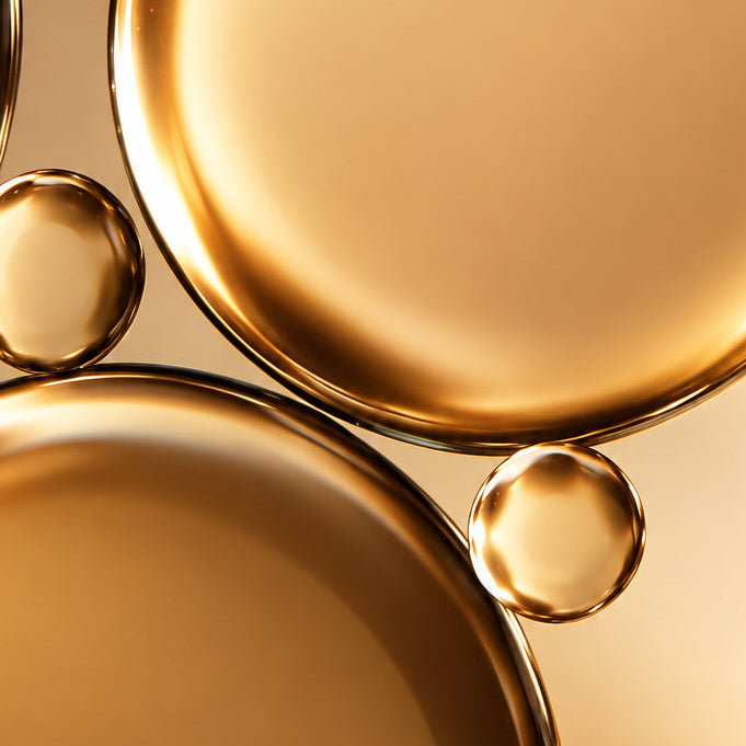 Close-up of gold-colored liquid droplets on a gradient background
